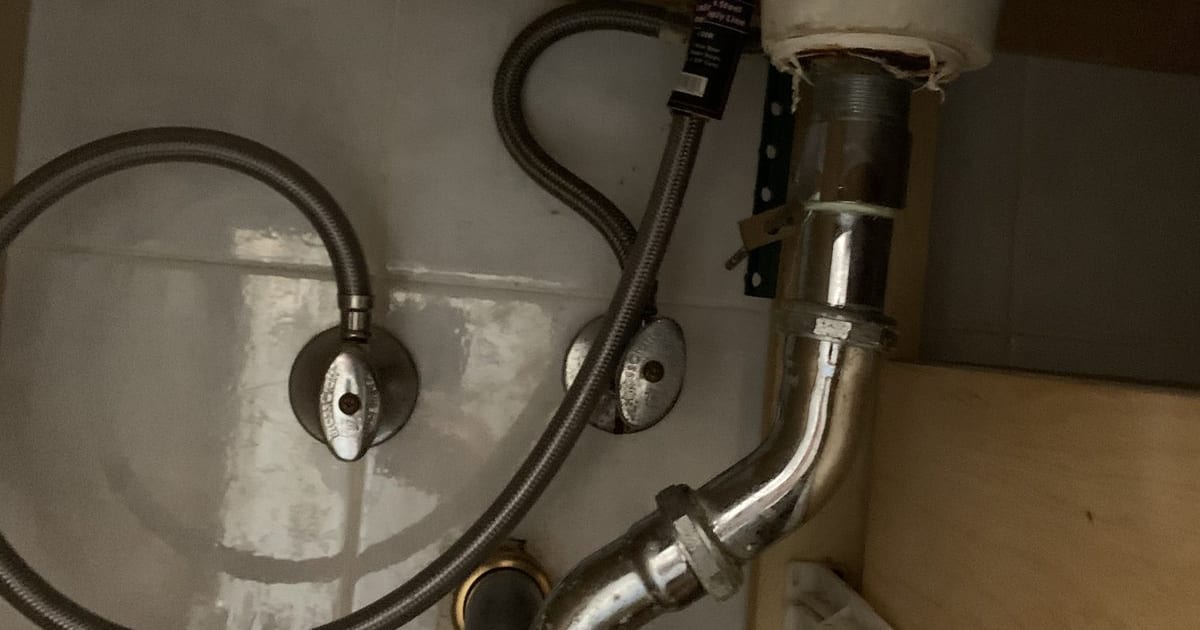 Under-sink P-trap and supply lines before replacement.