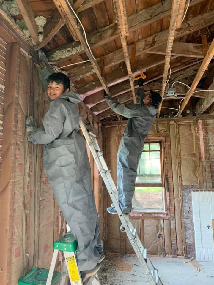 Two framers on ladders, smiling mid-build.