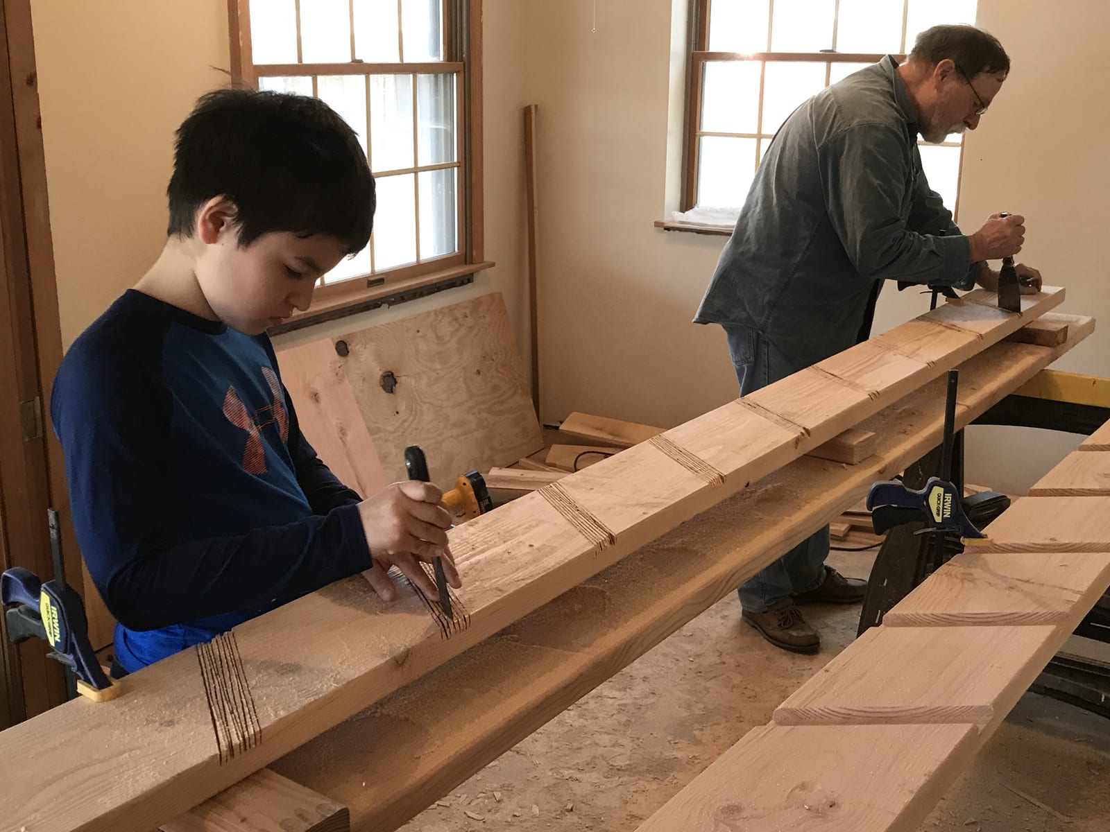 Jason teaching a young woodworker to chisel a mortise — hands-on mentorship.