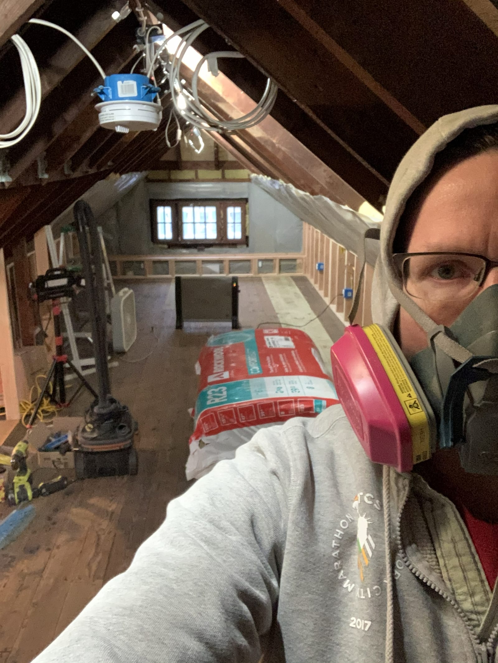 Jason Hammond in a respirator working in an attic remodel.