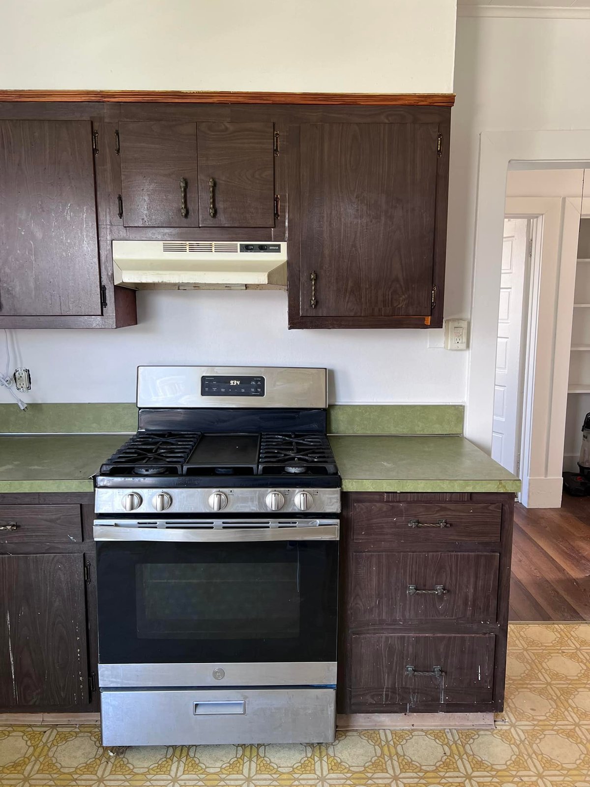 Original kitchen — dark cabinets, green laminate, vinyl floor. Everything had to go.