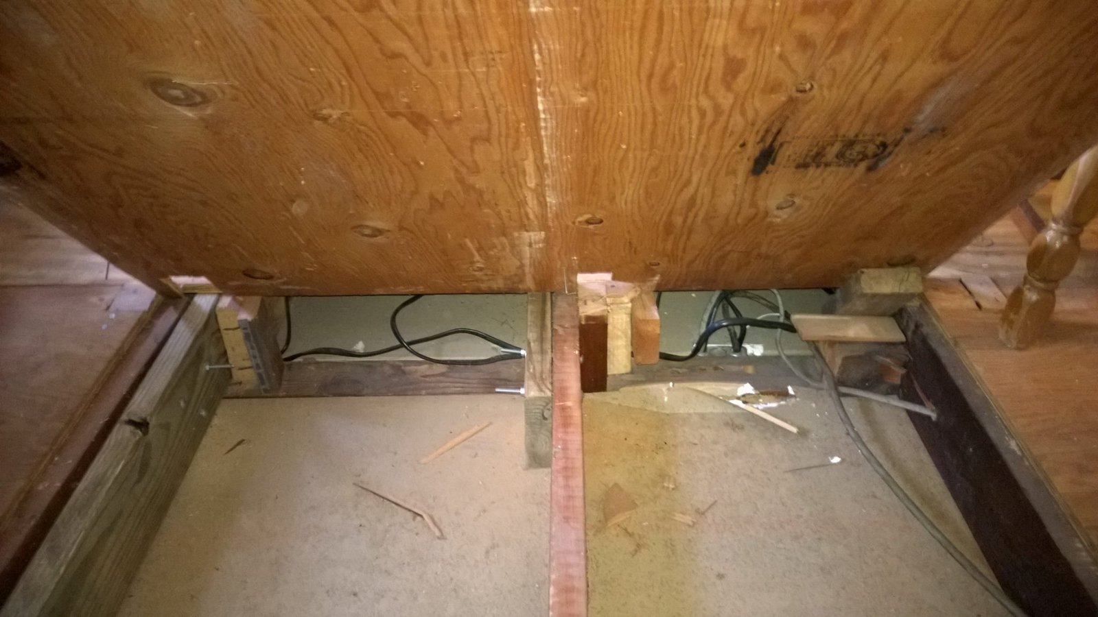 Raised the plywood subfloor on shims to level it and run new wiring underneath before locking it down.