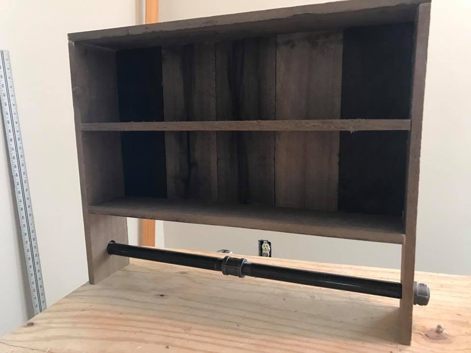 Towel-bar shelf unit on the bench in the shop. Pallet wood, dark stain, black pipe for the bar.