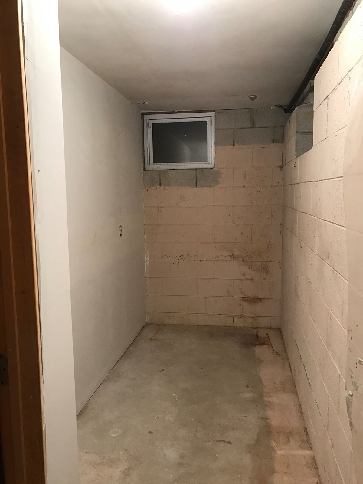 Block walls, slab floor, egress window. Decided early I wasn't going to frame this side — just clean it up.
