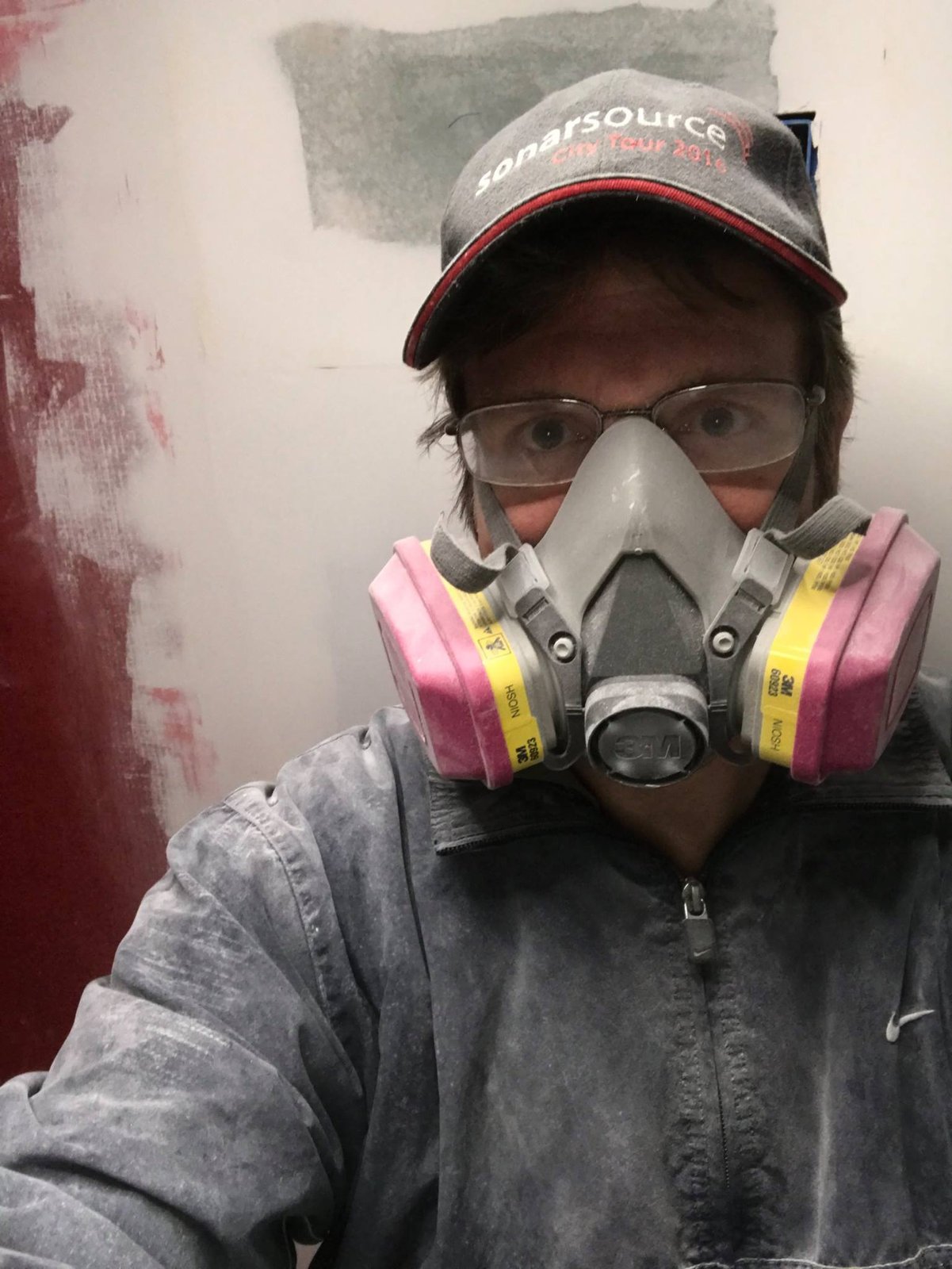 Respirator on, jacket covered in dust. Old paint and drywall coming down — this was a full gut, not a refresh.