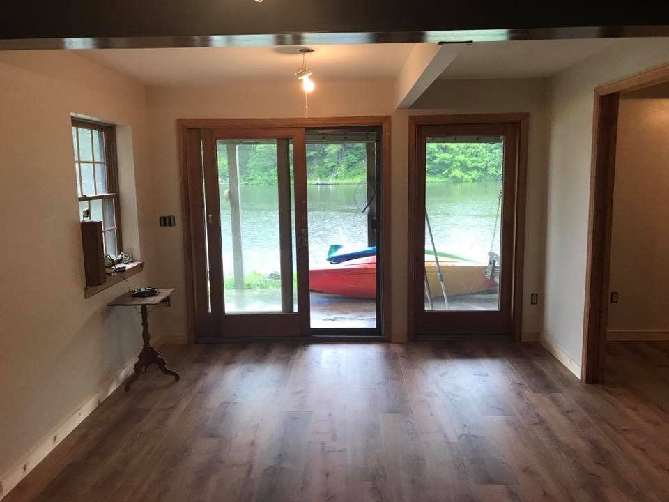 Lakeside room finished. New sliders, stained trim, vinyl plank. The view does most of the work.
