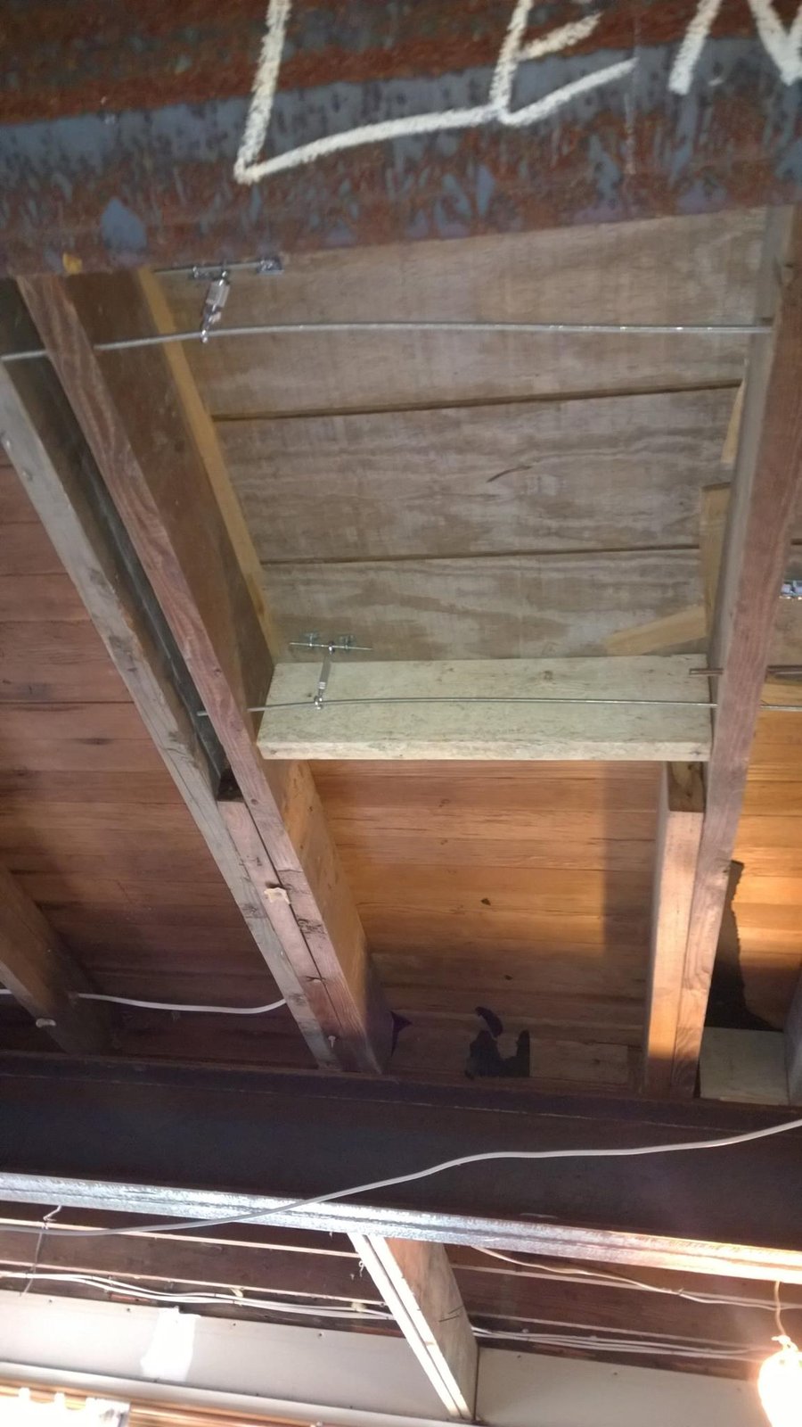 Turnbuckle tension cables were already in the joists. Left them alone — they were doing their job.