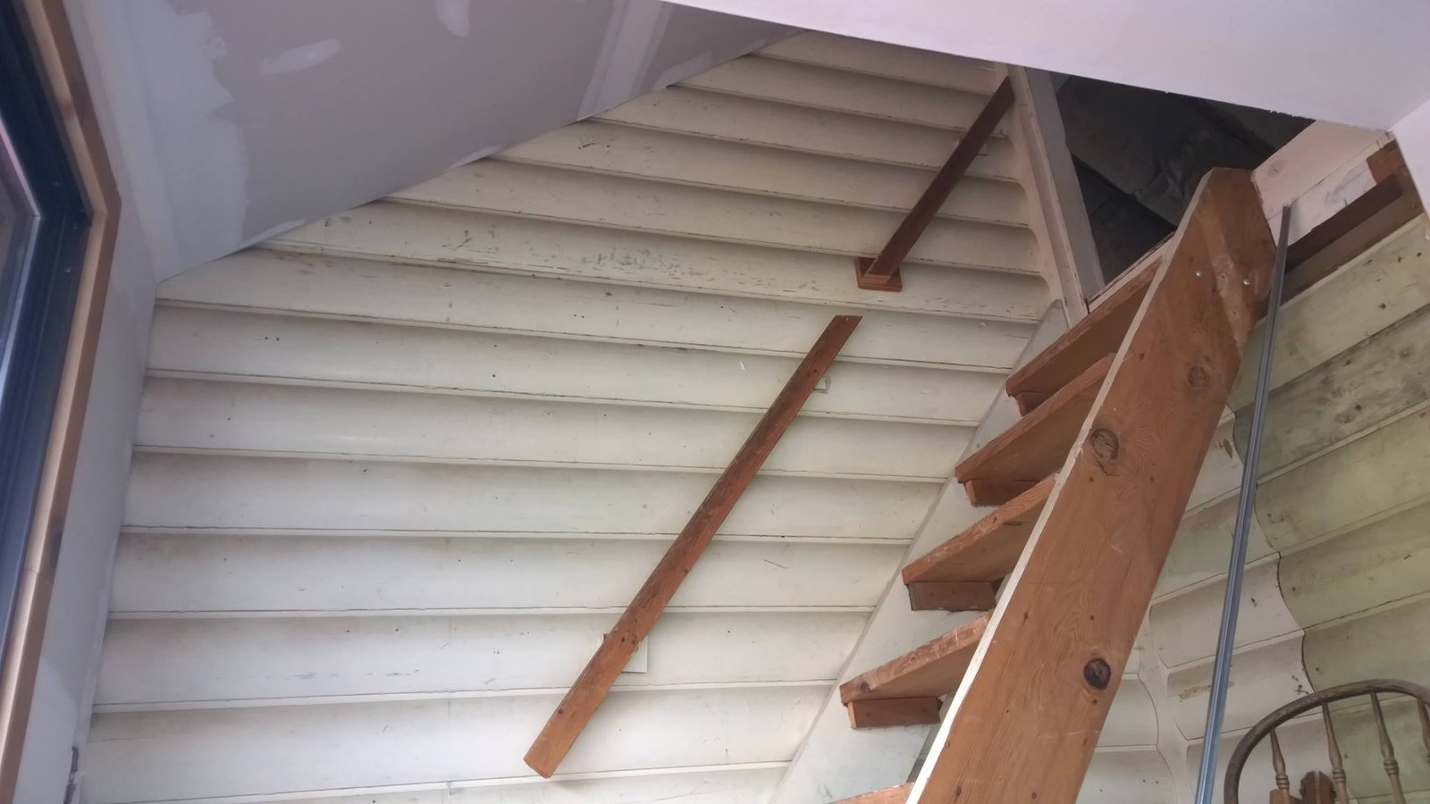 Stair stringer going in with the tongue-and-groove ceiling above. Loft stair early on.