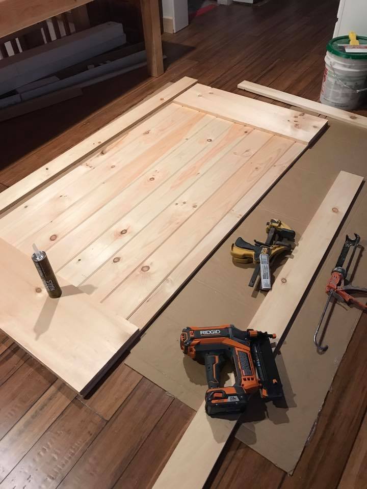 Building a barn door from pine planks. Nail gun, clamps, glue between the boards.