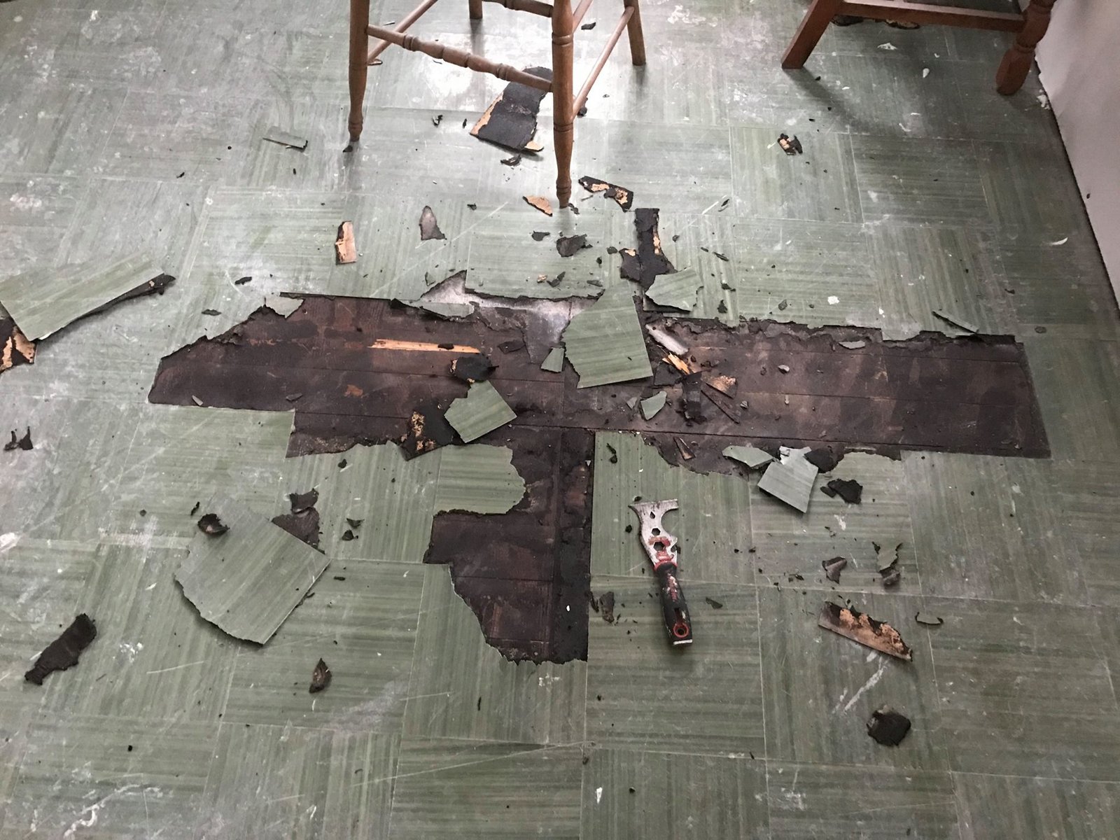 Scraping up the green vinyl tile to see what was under it. Original hardwood with tar paper still glued down.