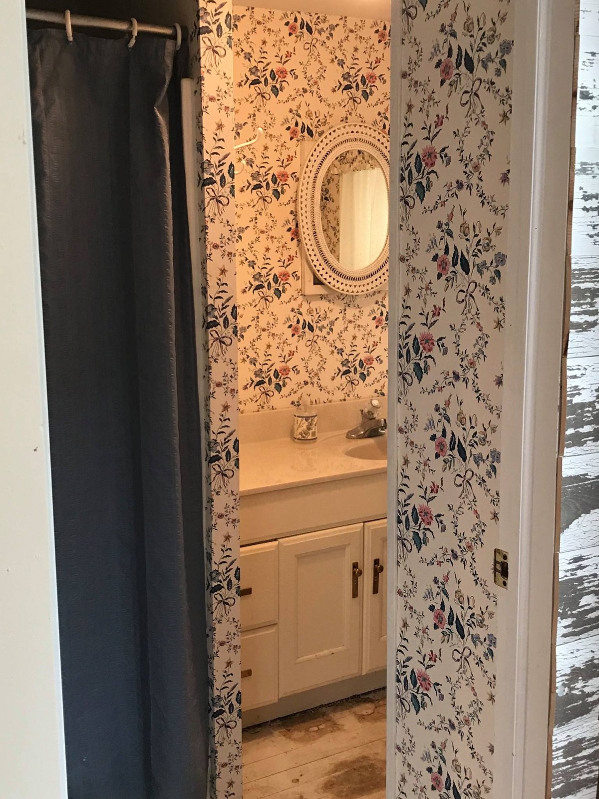 Starting point: floral wallpaper, oval mirror, builder vanity. Hadn't been updated in decades.