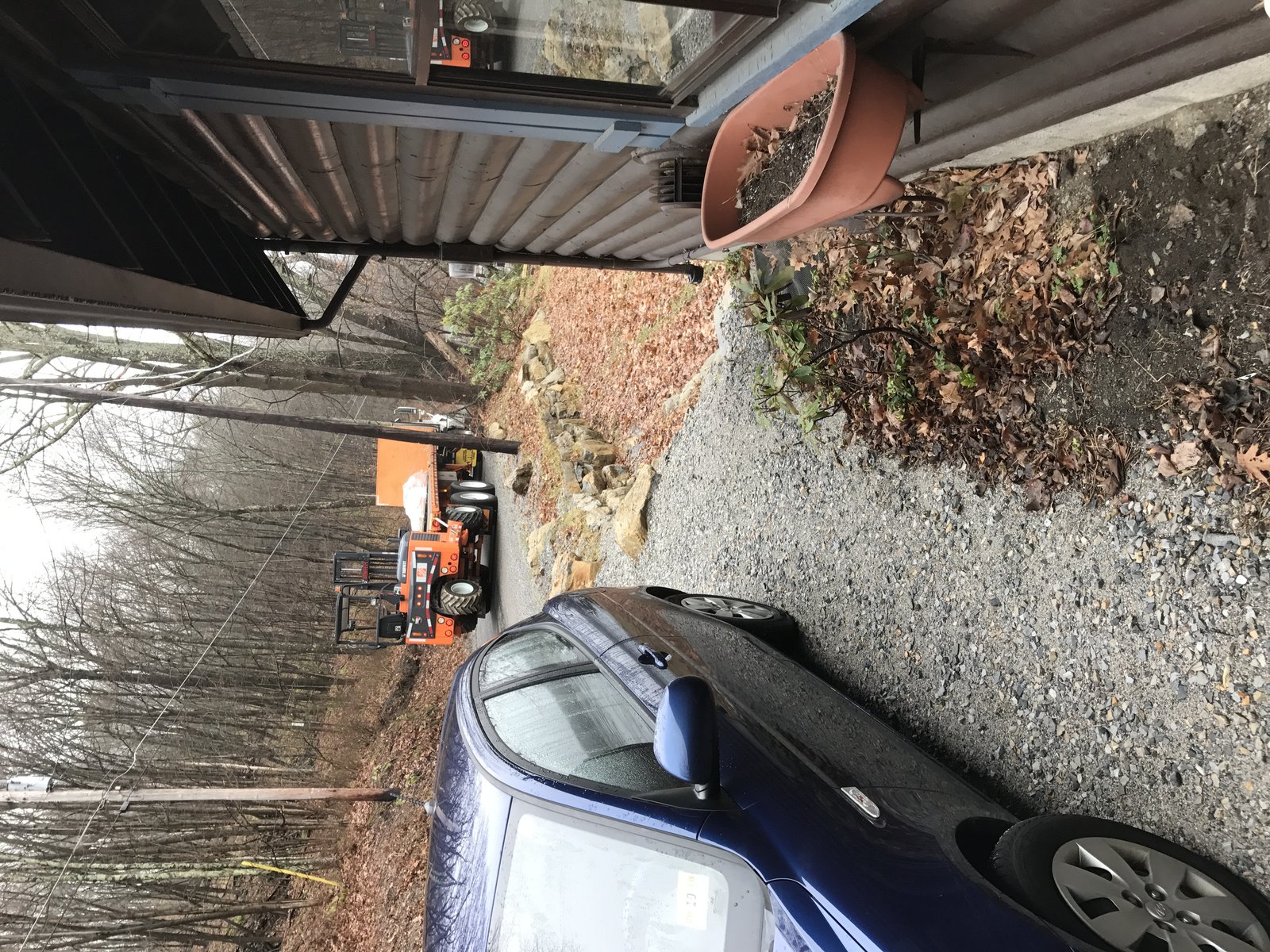 Rented skid steer staged in the drive — first thing I did was move the rock so I could get the machine in close.