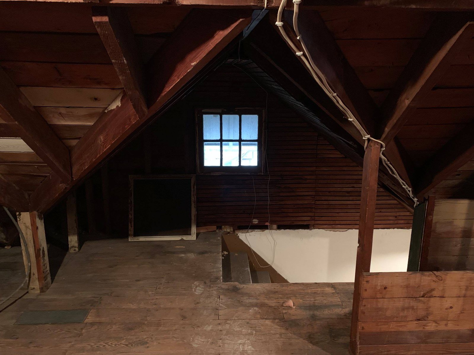 Attic as I bought it — exposed rafters, plank floor, gable window. No insulation worth the name.