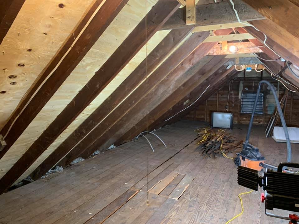 New plywood roof sheathing from the attic side, between original rafters and plank floor.