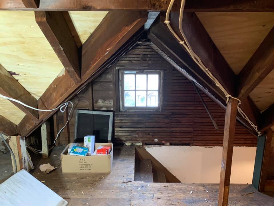 Original attic — lath wall, gable window, exposed rafters. Storage at best, nothing finished.