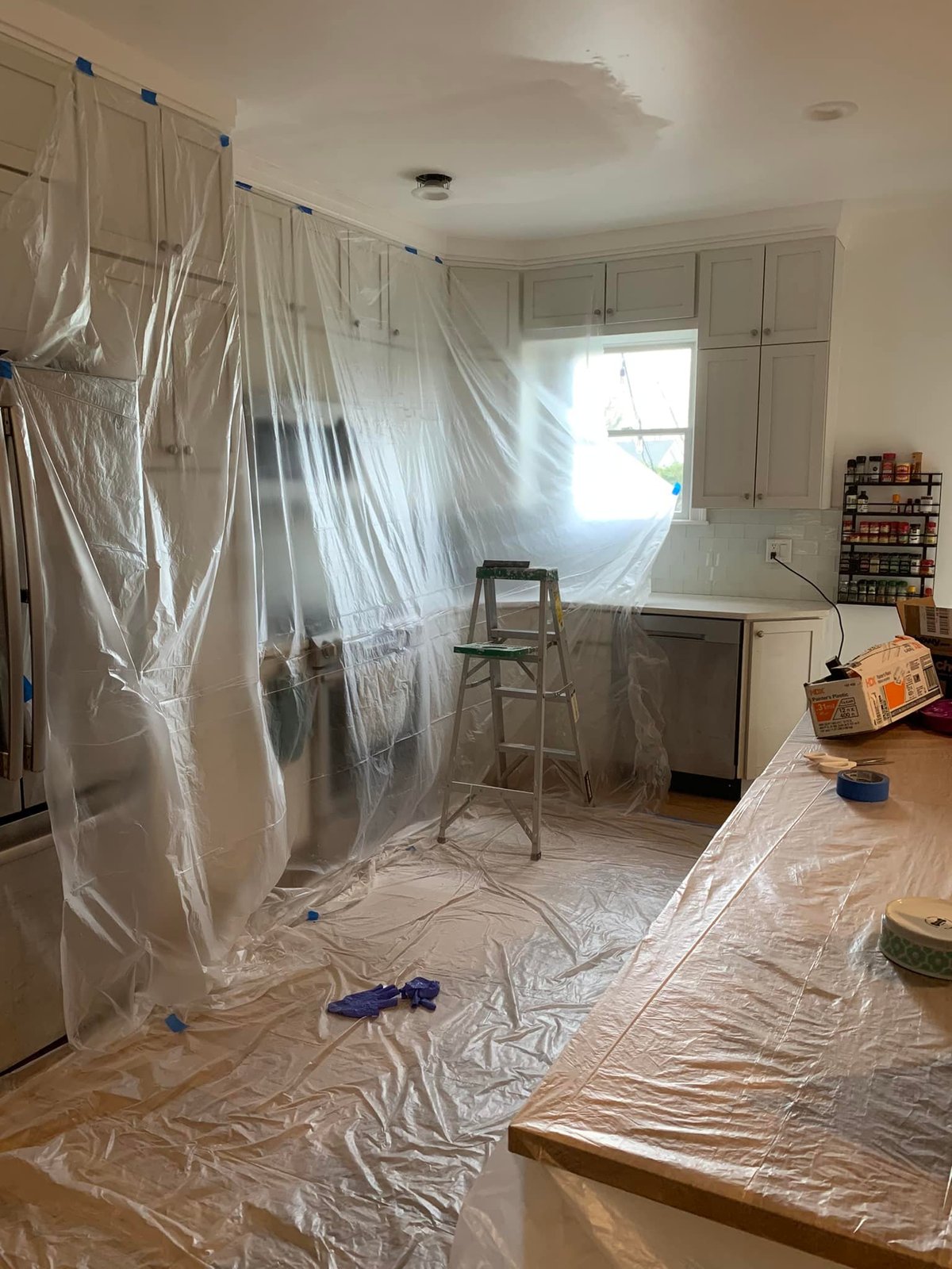 Kitchen taped off and tarped for the ceiling paint job. Cabinets stayed in place.