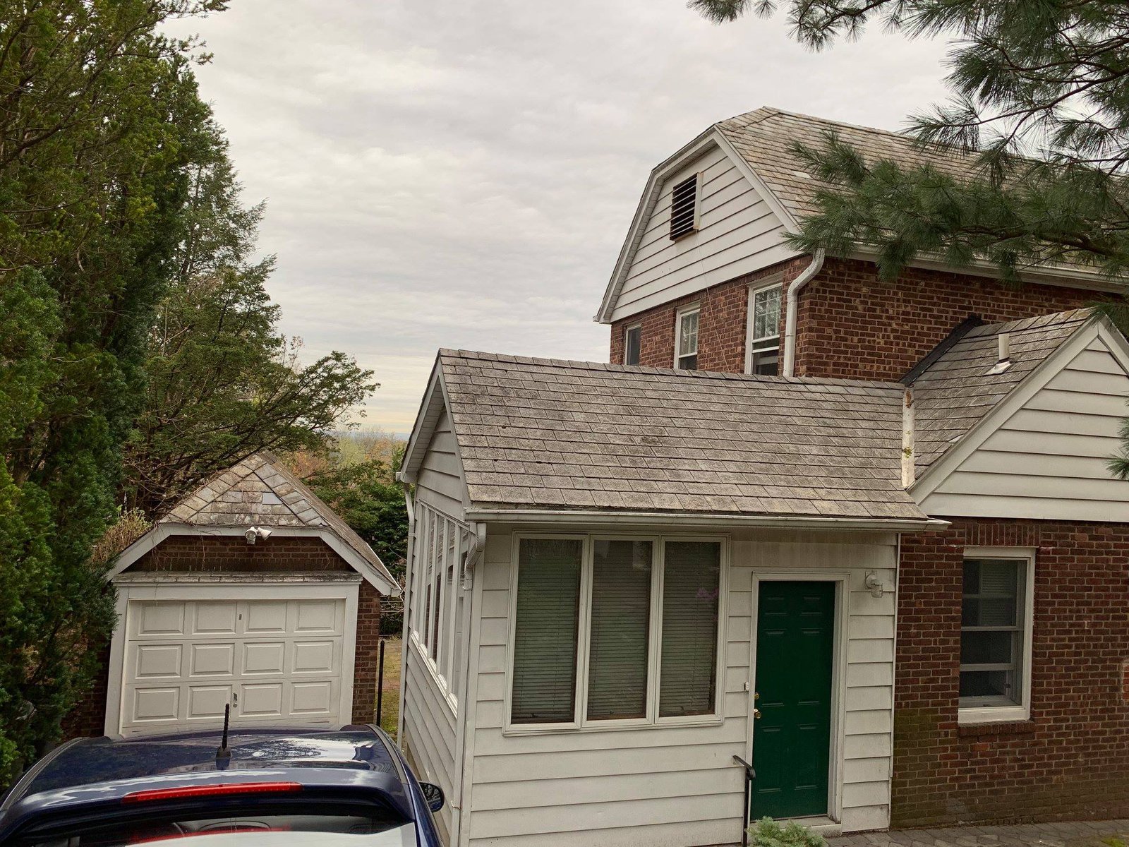 House from the back showing the aged cedar shake roof and the detached garage.