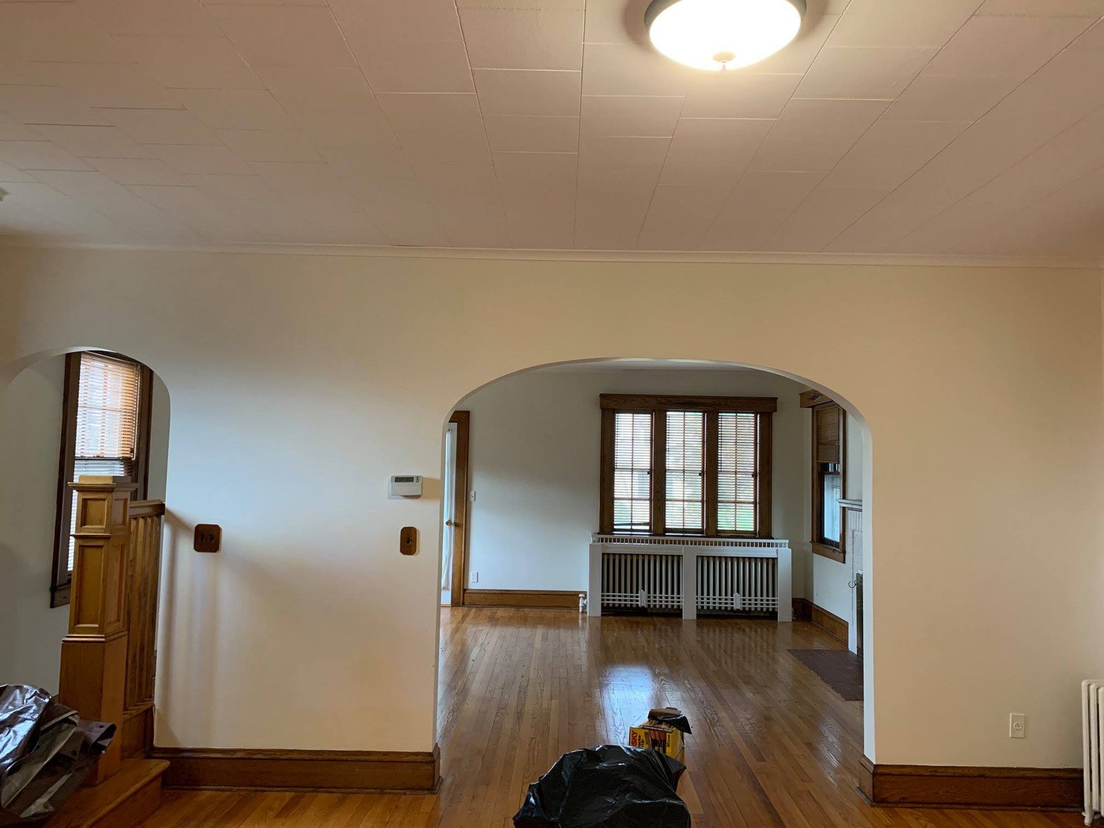 Living room as I bought it — pressed tin ceiling, original archway, and good bones.