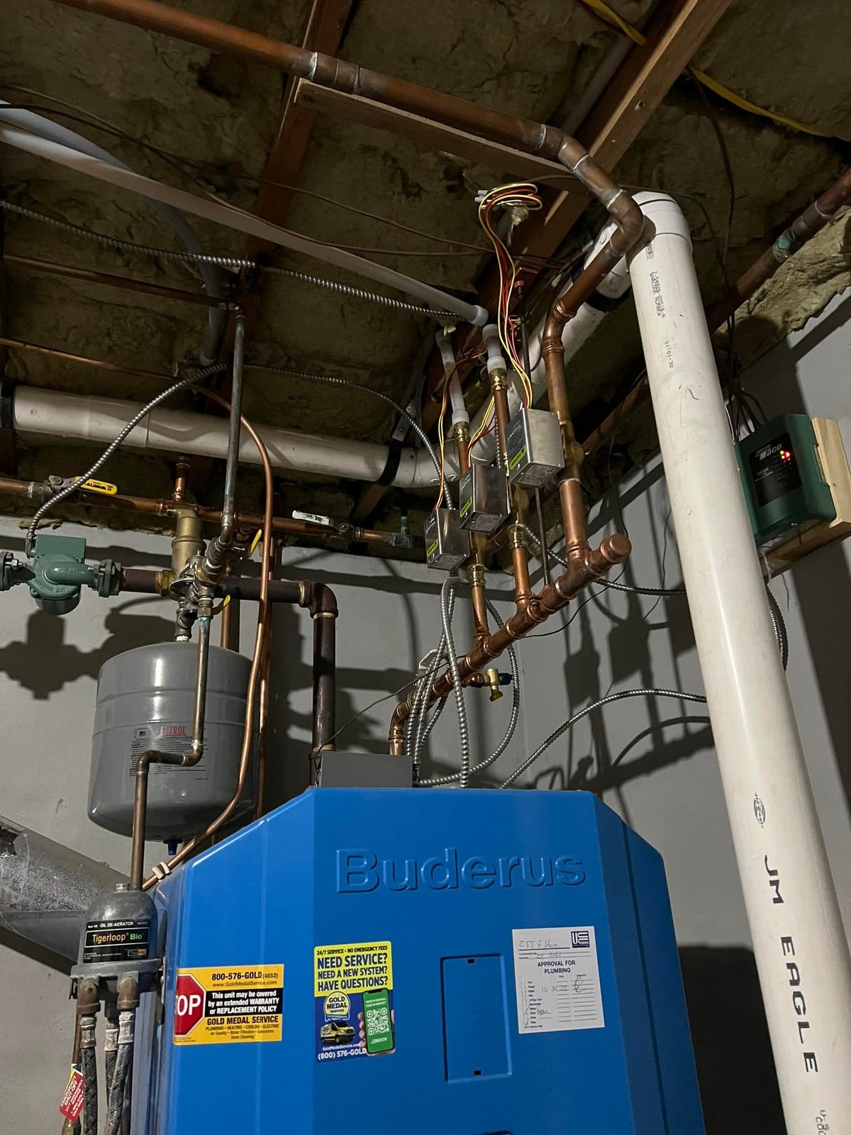Buderus boiler with the rebuilt copper manifold, zone valves, expansion tank, and circulator.