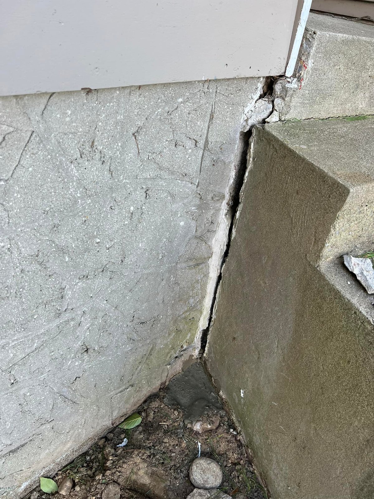 The concrete steps had pulled away from the foundation — that vertical crack was funneling roof water straight at the wall.