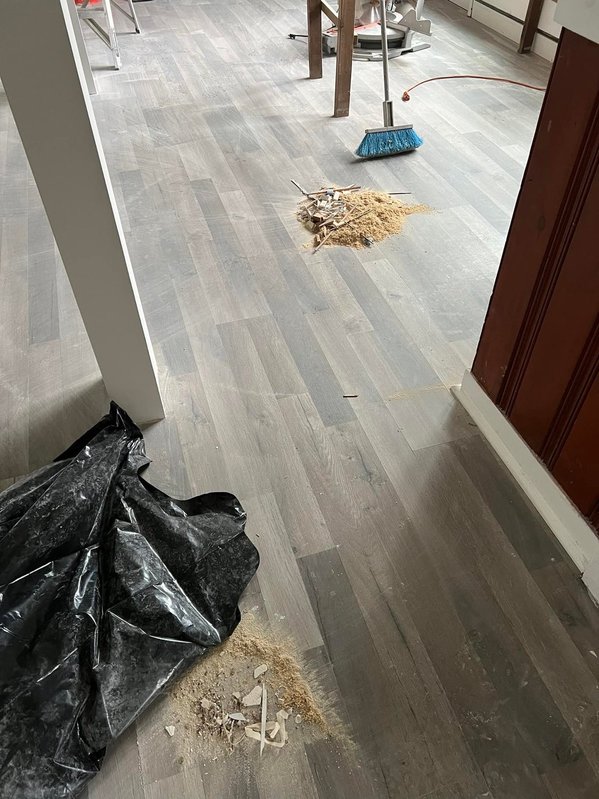 Sweeping up offcuts after laying the gray vinyl plank.