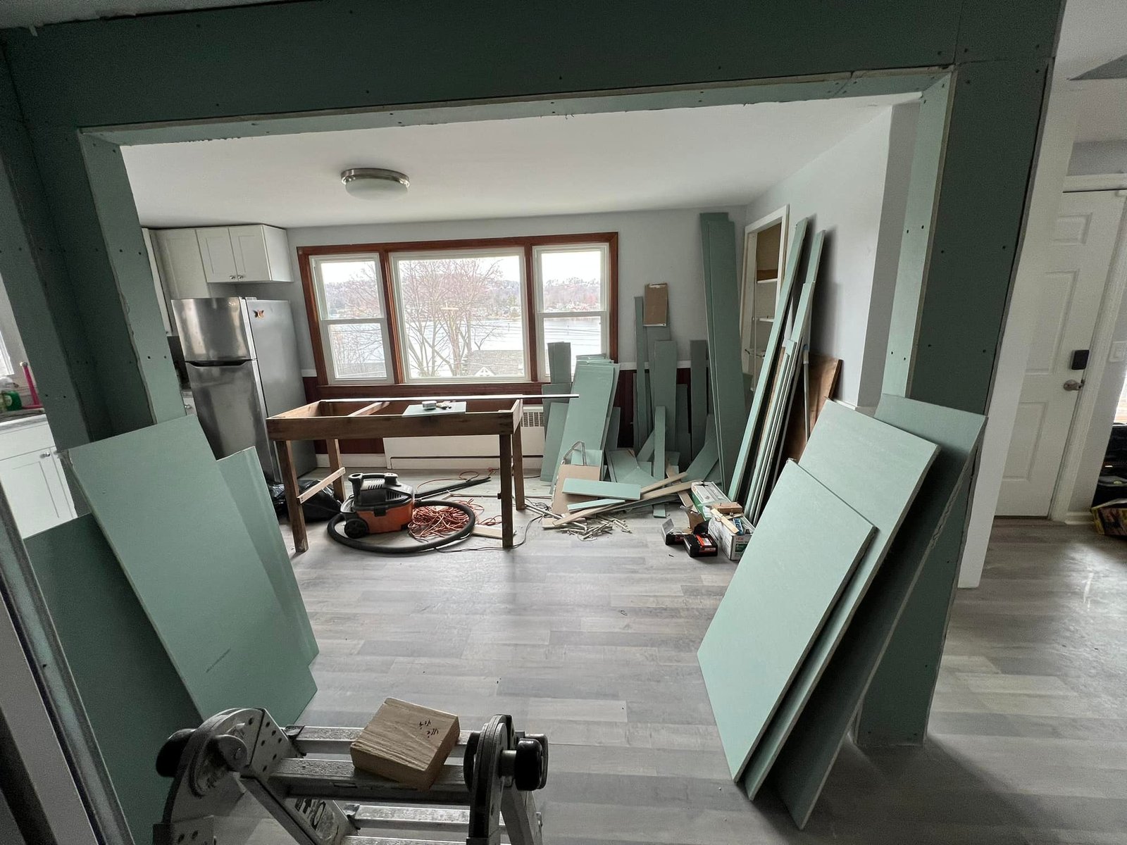Looking through the new opening into the kitchen with green board stacked for the patch-in.