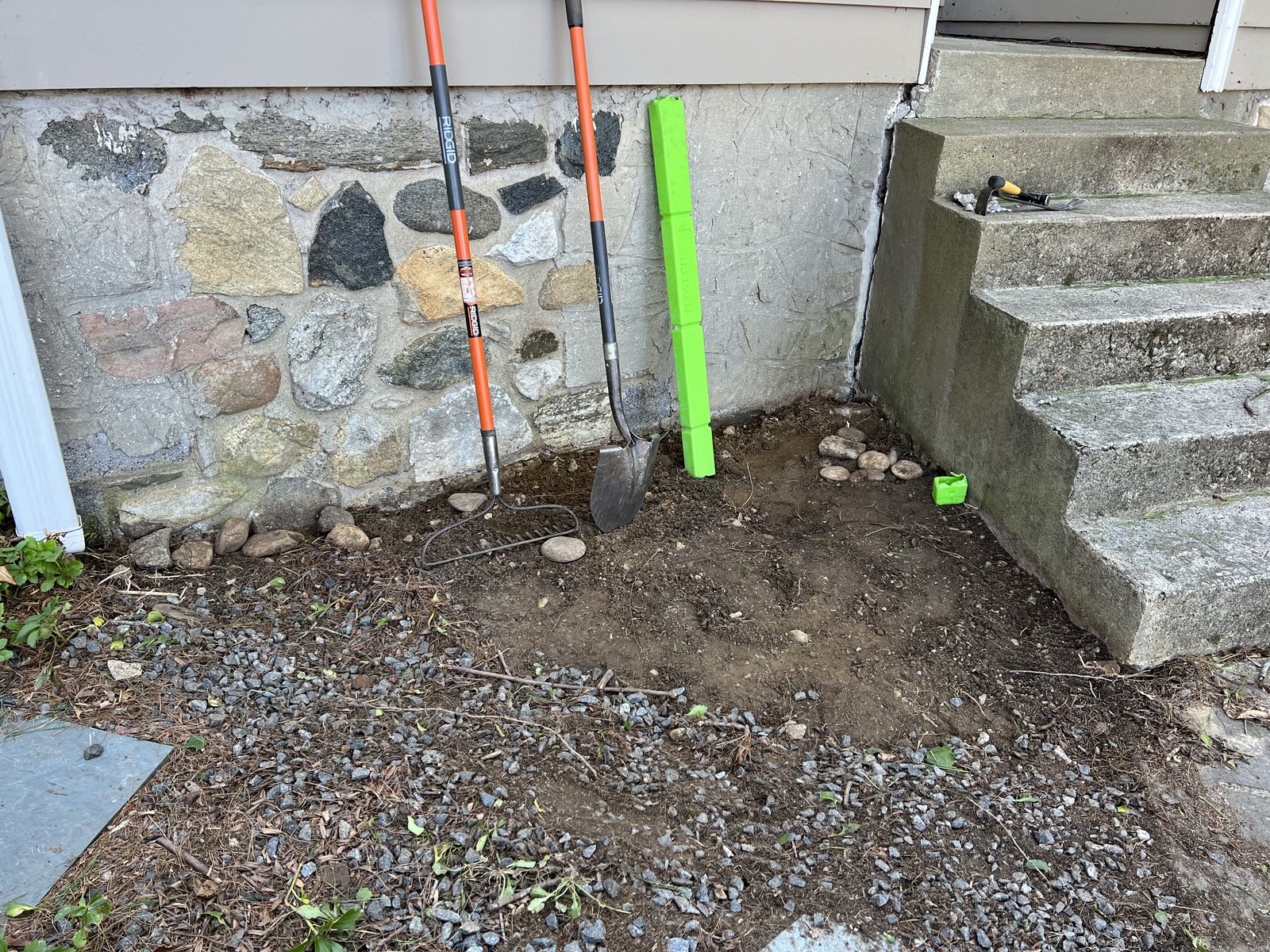 Cut into the bank beside the old concrete steps to set a new stone landing.