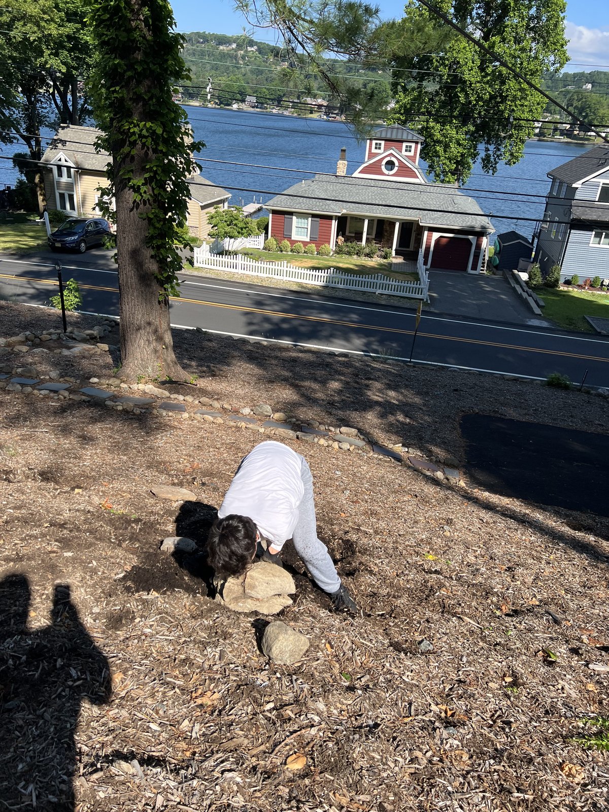 Helper setting fieldstones into the hillside above the lake road.