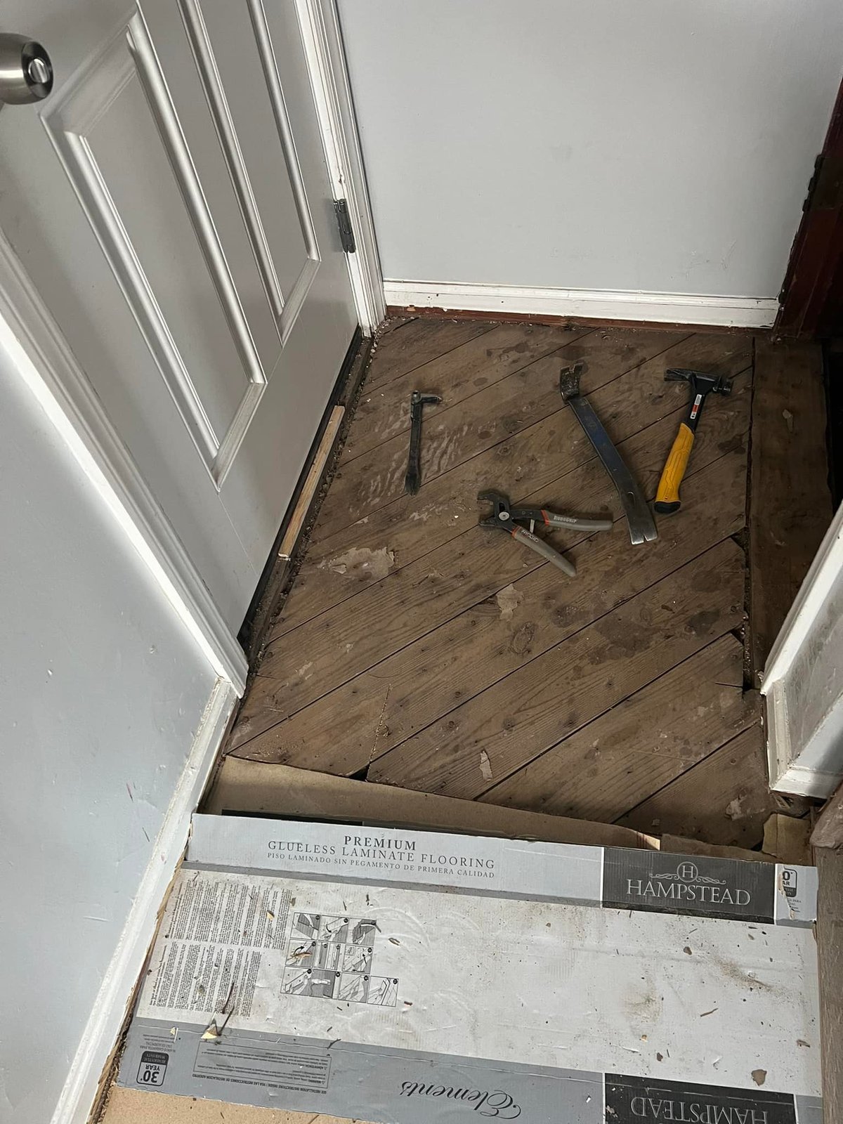 Old floor pulled back to the plank subfloor with new Hampstead Elements boxes staged.