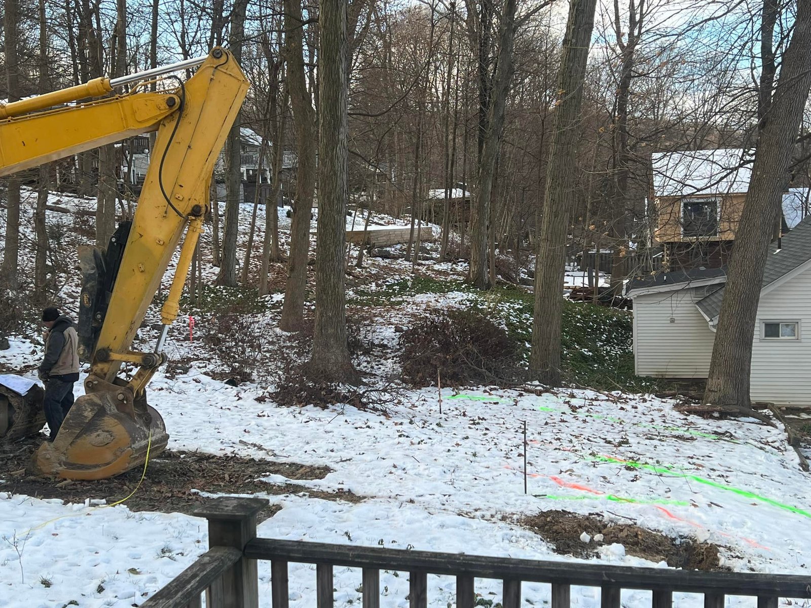 Excavator parked on the snowy lot with utility lines marked. Cold start to a big job.