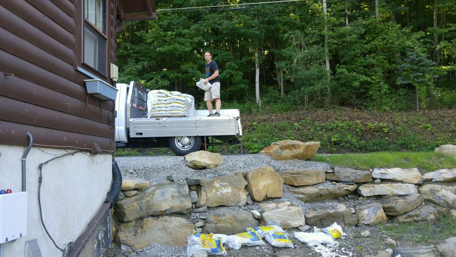 Unloading bags of gravel onto the new wall site for backfill behind the stone.