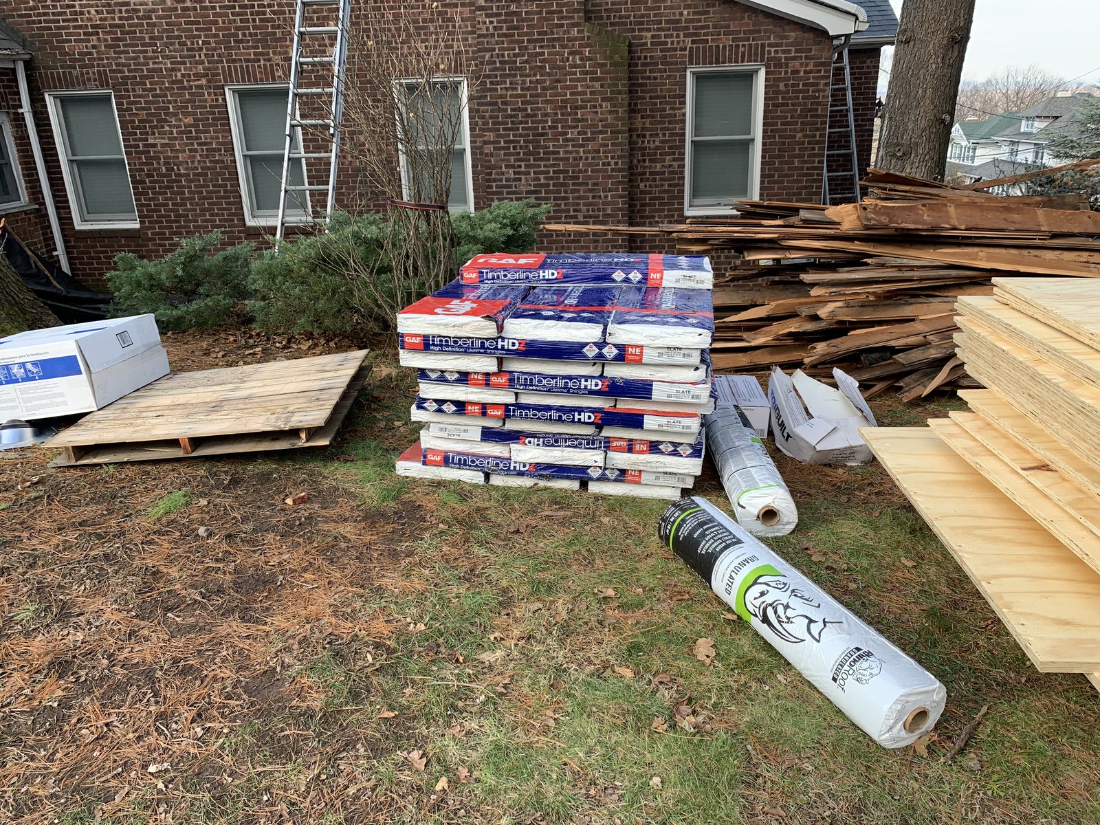 Shingles, underlayment, plywood, and the old torn-off wood all staged together so the crew could just work.